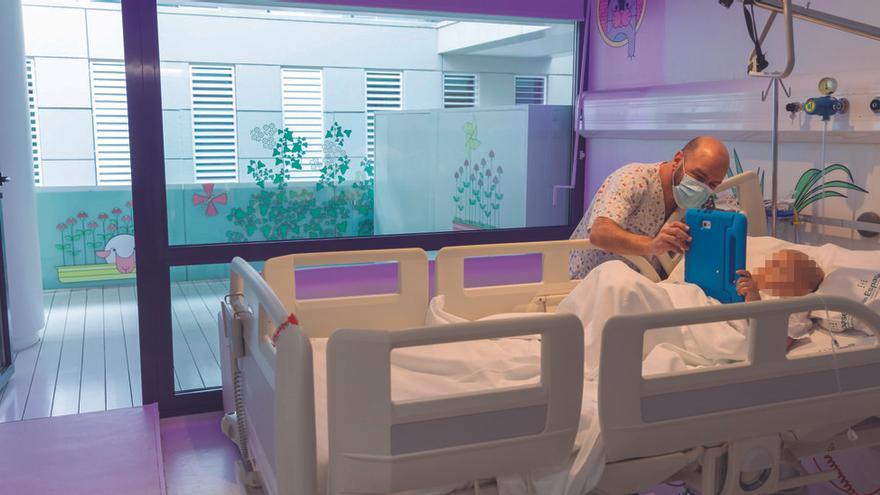 Un sanitario atiende a un menor con cáncer ingresado en la unidad de oncología infantil