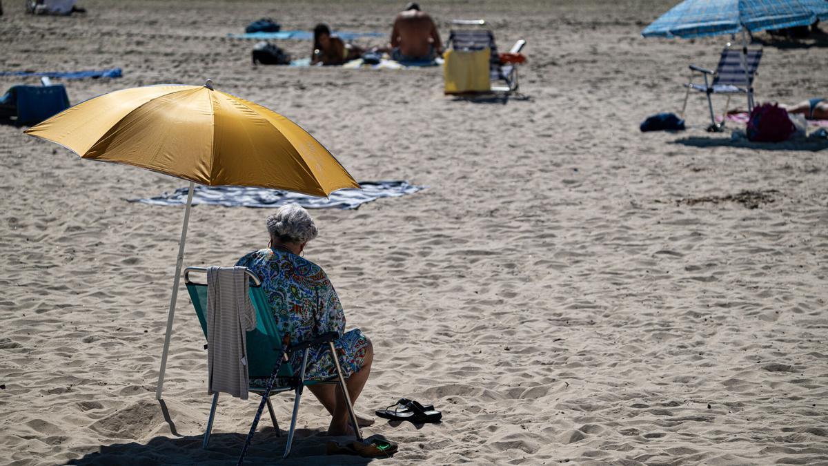 Mujer en la playa bajo una sombrilla.