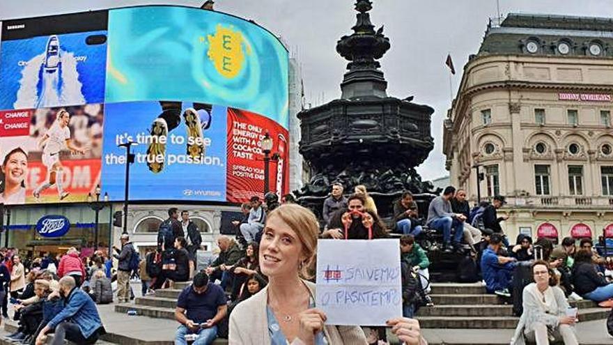 Una joven, con un cartel en solidaridad con O Pasatempo en Piccadilly Circus, en Londres.