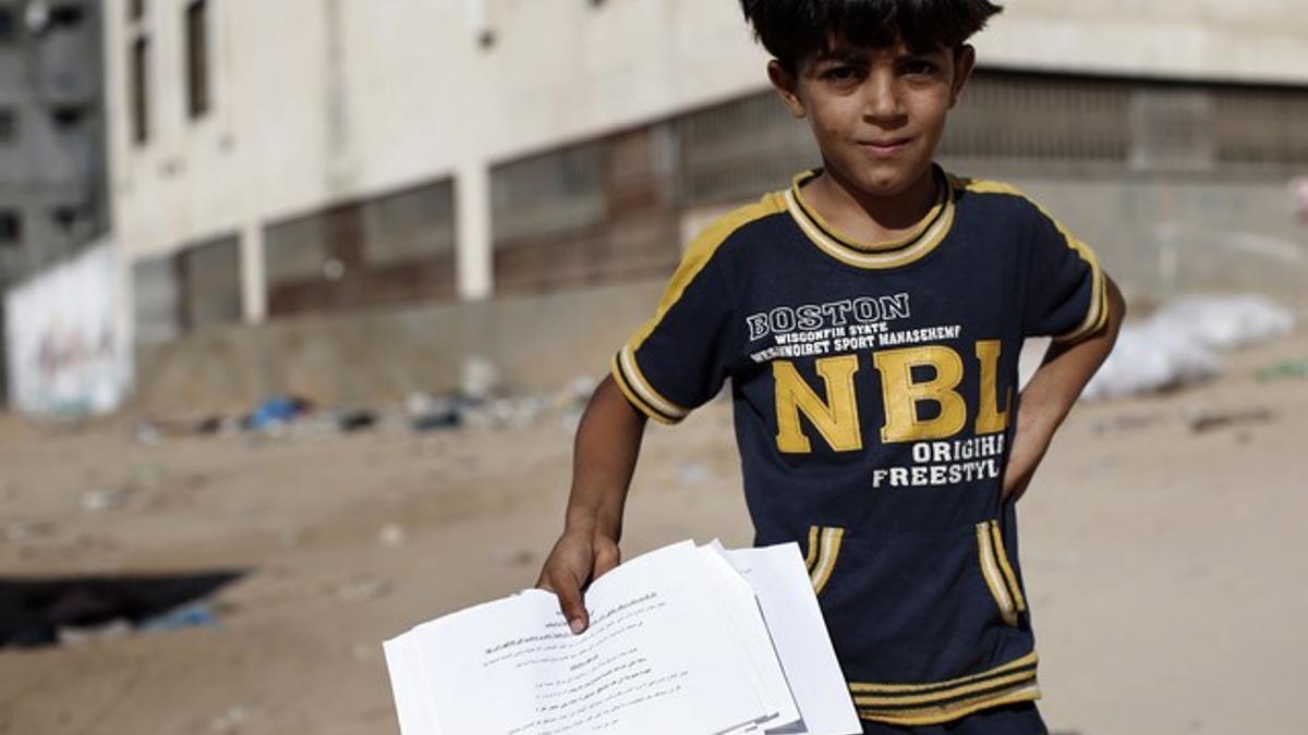 Un niño palestino muestra el papel lanzado por el Ejército israelí en el que ordenan la evacuación, este miércoles en Gaza.