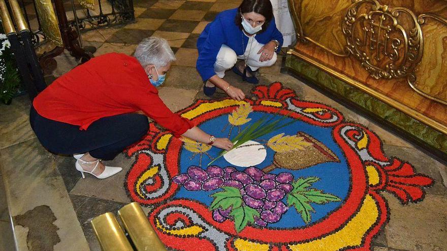 Maite Muiña e Isabel Loriente, ayer, con los últimos retoques a la alfombra principal, en el altar.