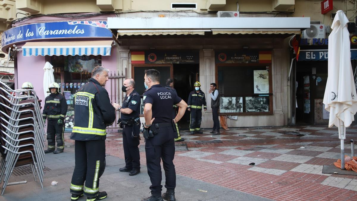 Bomberos y policías locales a las puertas del bar El Puerto, donde se ha registrado un incendio esta mañana de miércoles.