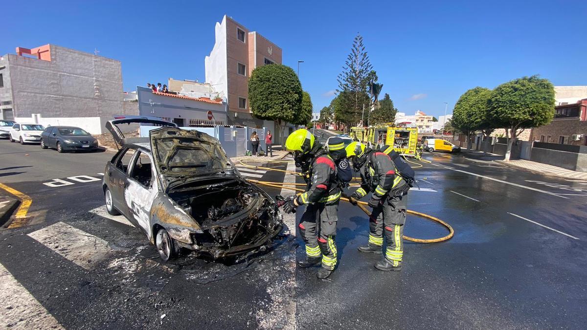 Bomberos del Parque de Arinaga apagan el fuego en un coche en la calle Roque Aguayro en Agüimes.
