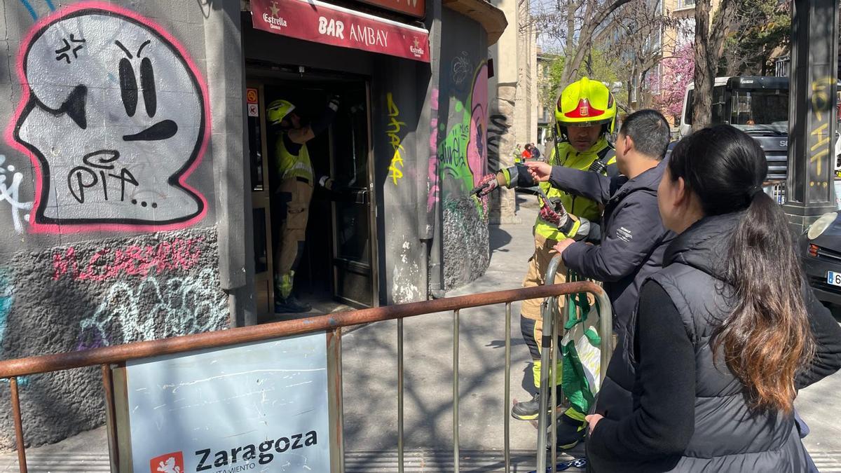 El propietario de un bar explica a los bomberos dónde están sus pertenencias.