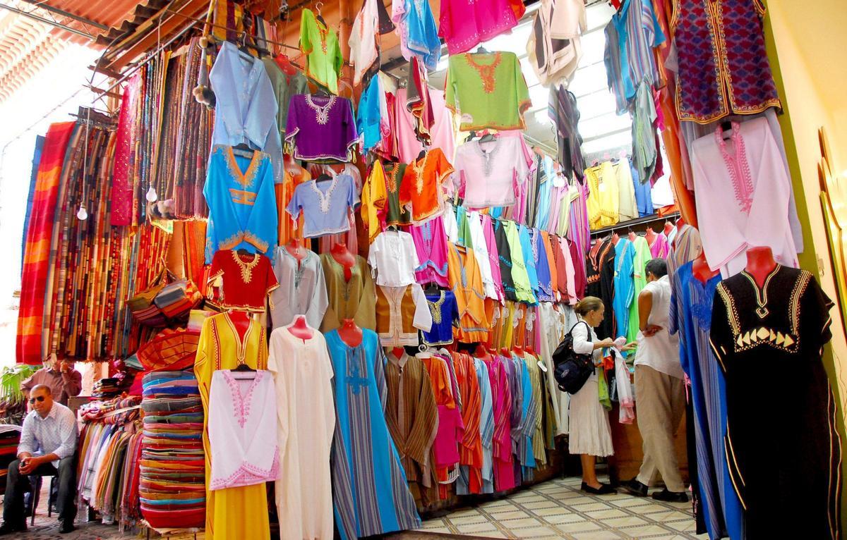 Una pareja de turistas conversan con un vendedor en un mercado de Marrakech.