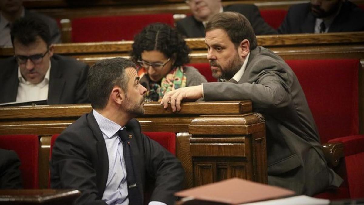 El 'conseller' Santi Vila conversa con el líder de ERC, Oriol Junqueras, en el Parlament.