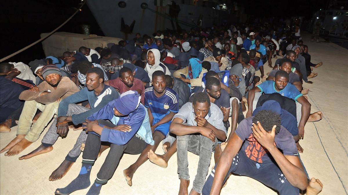 Un grupo de refugiados esperan en una base naval de Libia después de ser resctadaos en el Mediterráneo.