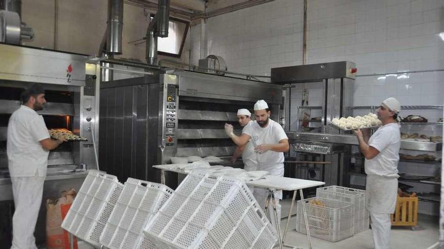 Luis Iglesias (centro) trabajando en la elaboración de pan en su obrador. En el recuadro, bollas del pan de munición. // D. P.