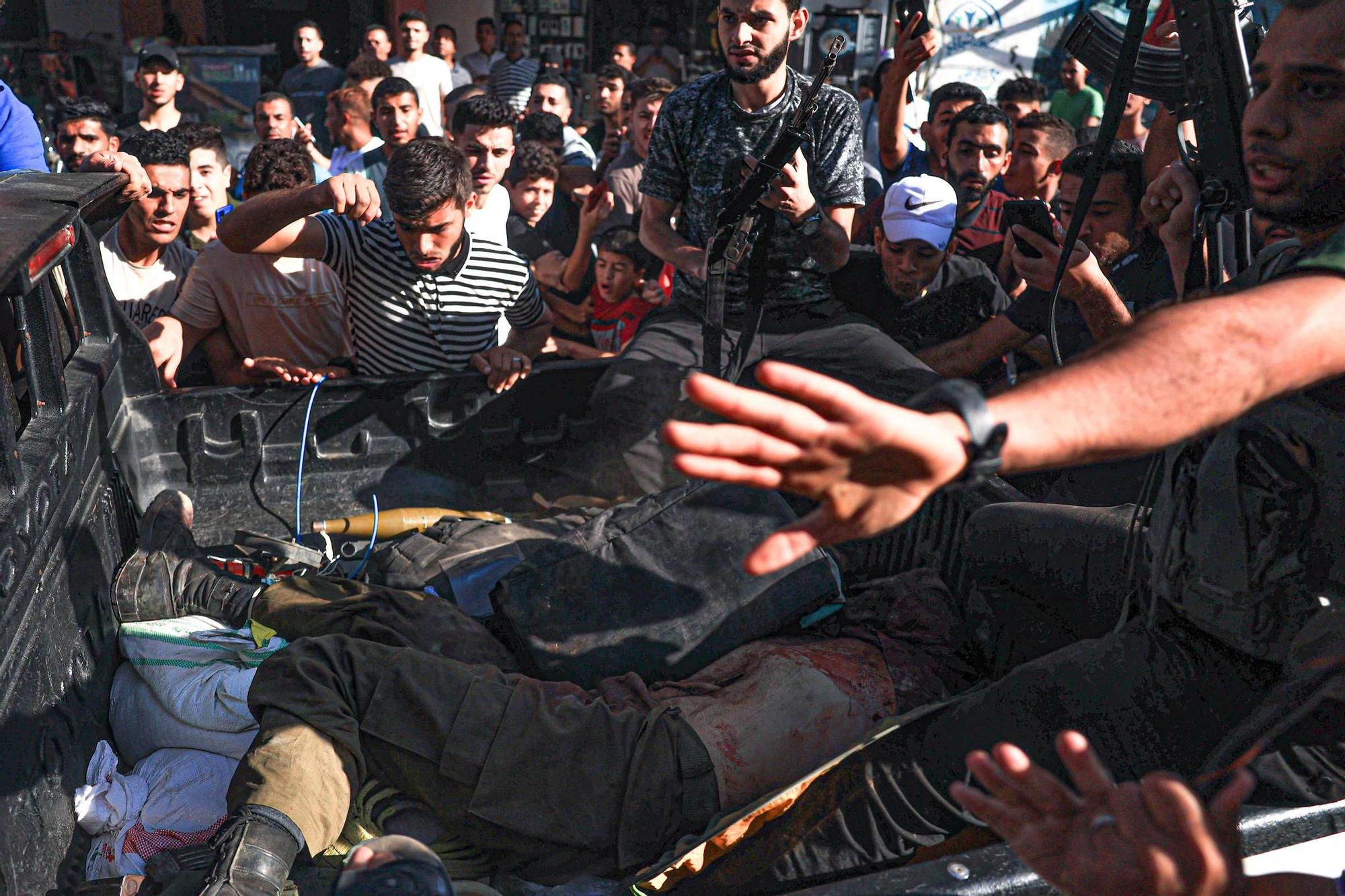 Palestinos rodean un camión que transportaba dos soldados israelís muertos en la parte trasera, en Khan Yunis, en el suroeste de la Franja de Gaza.