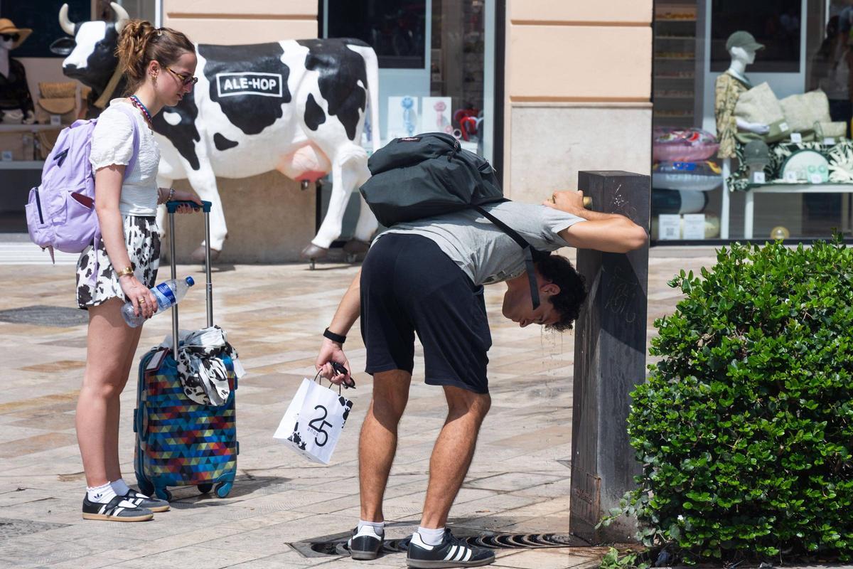 Un joven aliviándose del calor ayer bajo una fuente en València.