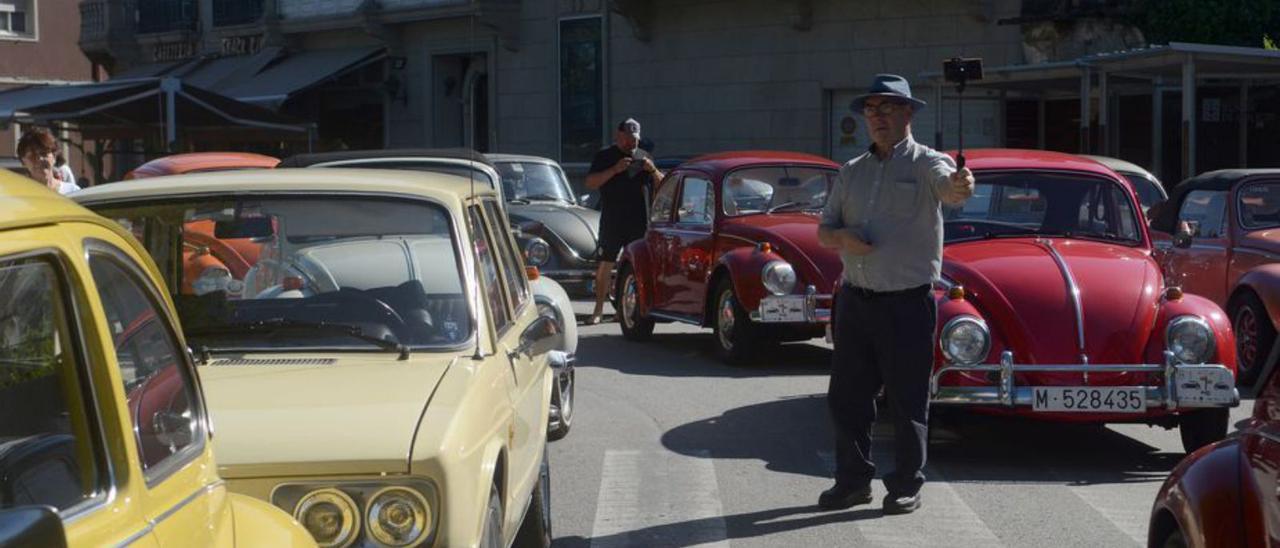 Un hombre toma una fotografía con los vehículos tras él.   | // NOÉ PARGA