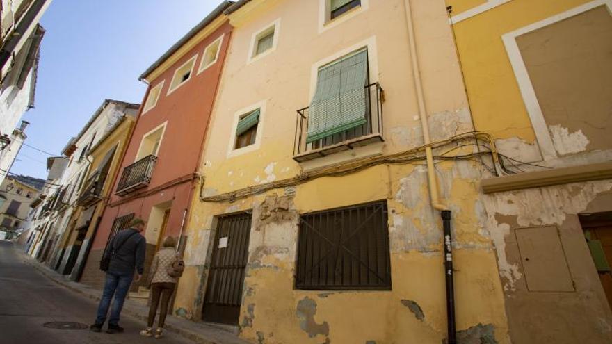 Una pareja lee el cartel fijado en la puerta de la casa, en el que se advierte que tiene dueñas tras un intento de okupación. | PERALES IBORRA