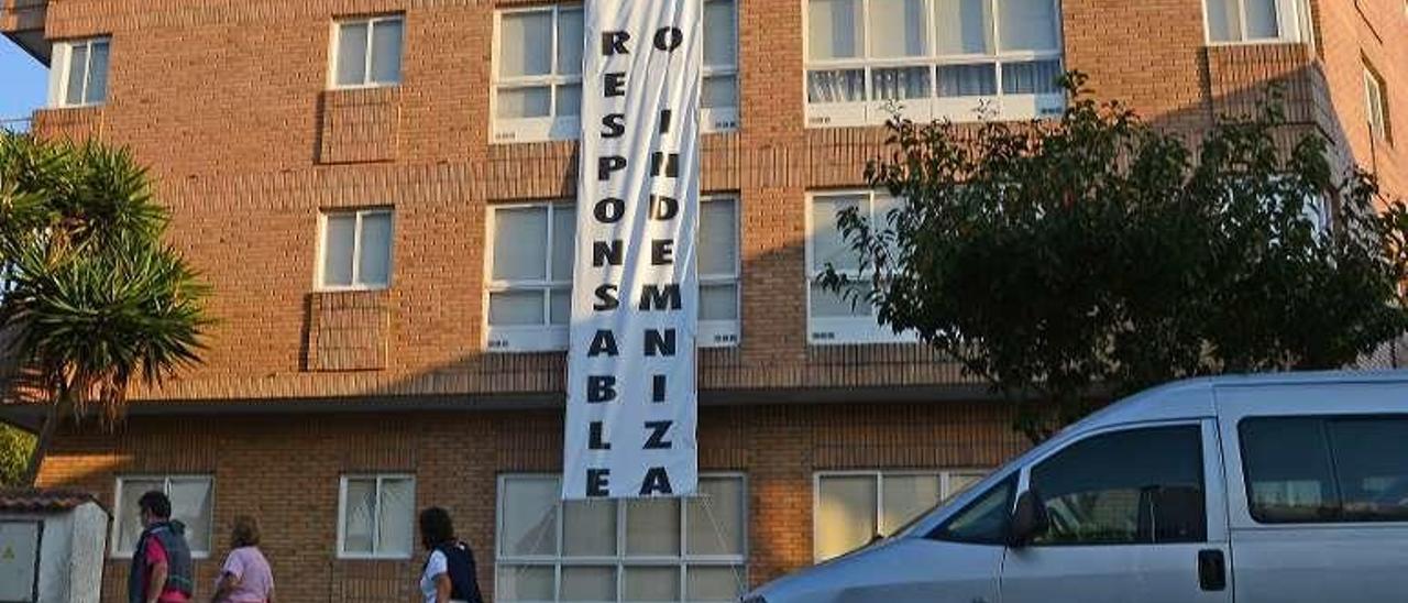 Pancarta colgada en el edificio, en la que los vecinos piden indemnizaciones o la legalización del inmueble. // G.N.