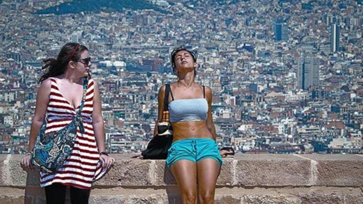 Dos turistas soportan el calor de espaldas a la espectacular vista de la ciudad.