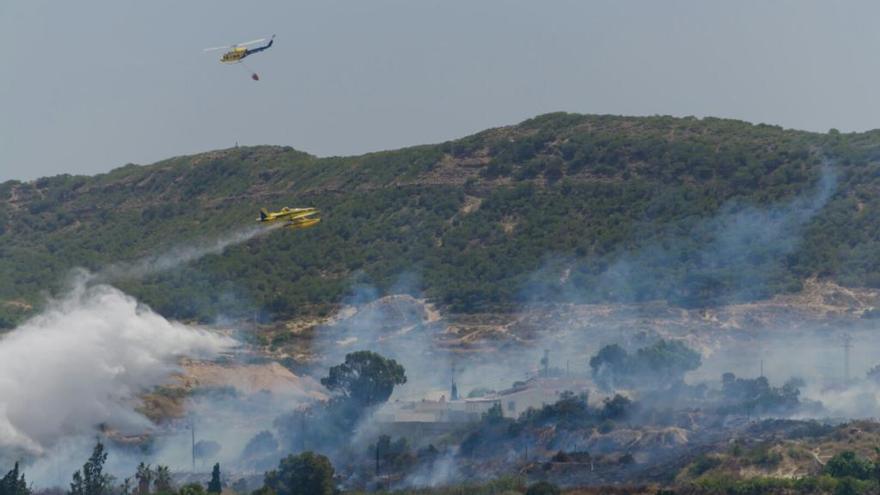 Dos unidades aéreas de los bomberos vacían su carga de agua sobre el terreno quemado