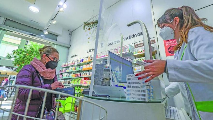 Una clienta compra un test de antígenos en una farmacia de València.