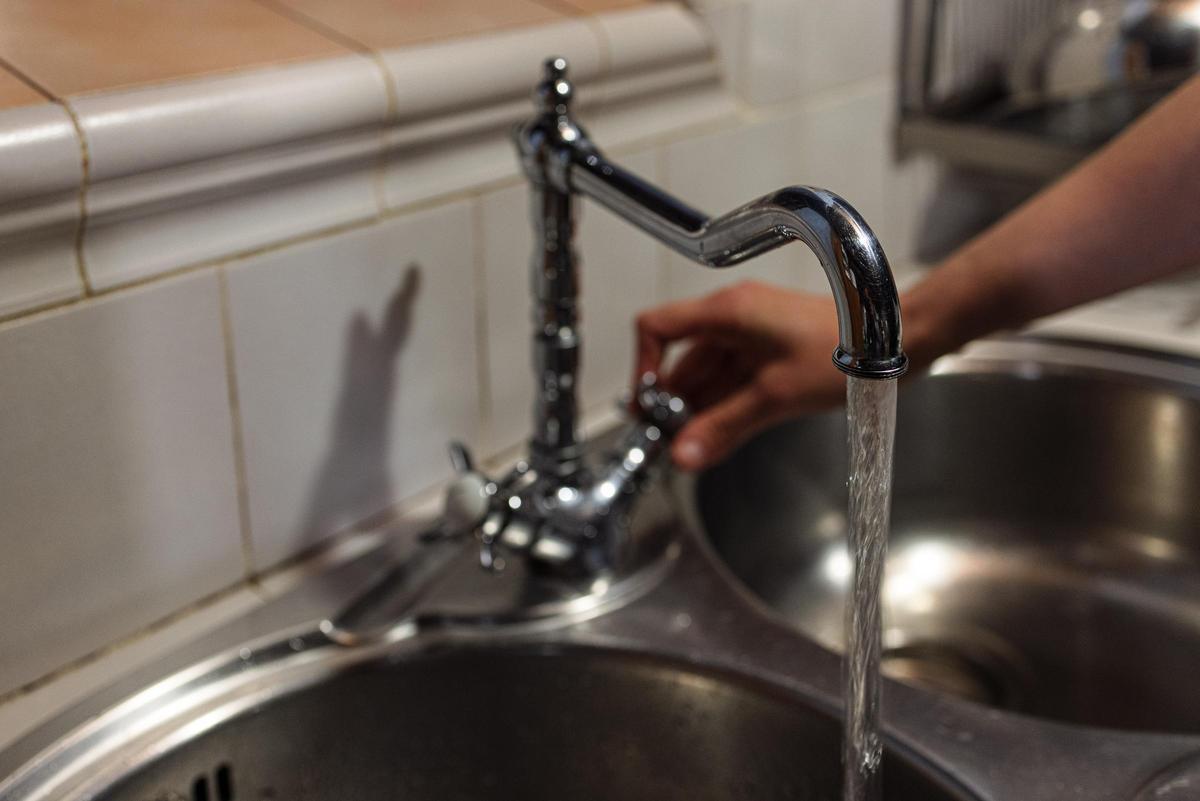 Una persona obre una aixeta de la cuina.