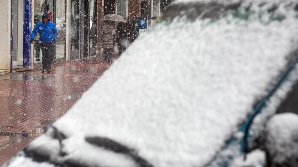 Varias personas caminan por la calle mientras nieva