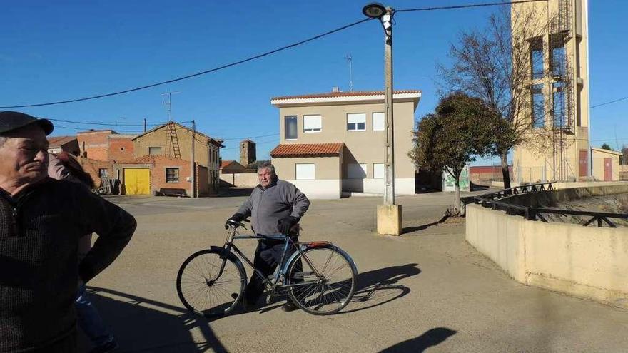 Ángel Fernández, alcalde de Santa Colomba de las Monjas, cruza en bicicleta delante del edificio.