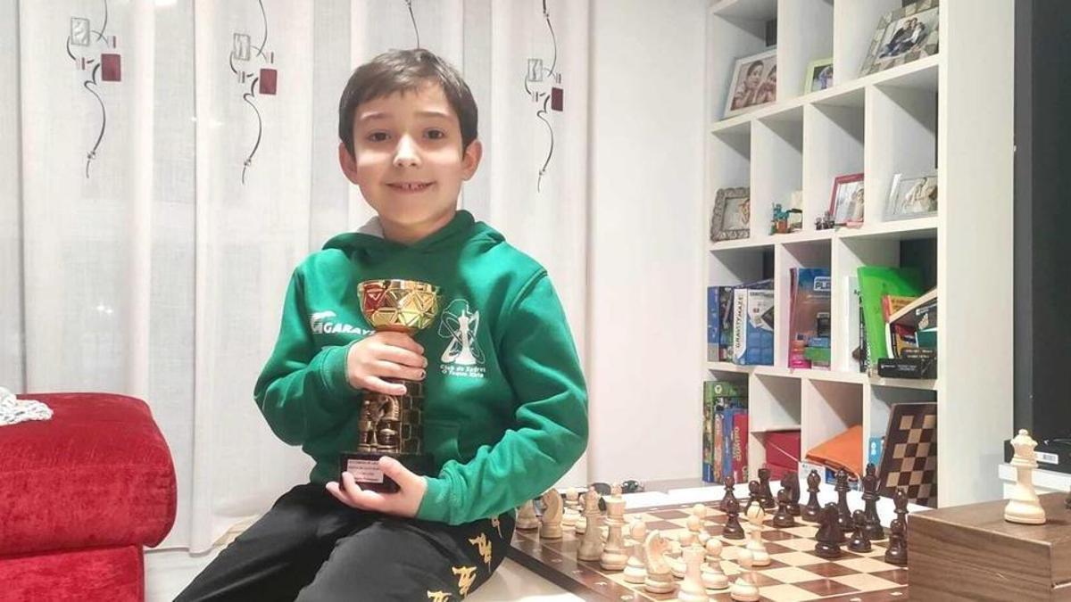 Roi Bello, con uno de sus trofeos y su inseparable tablero de ajedrez