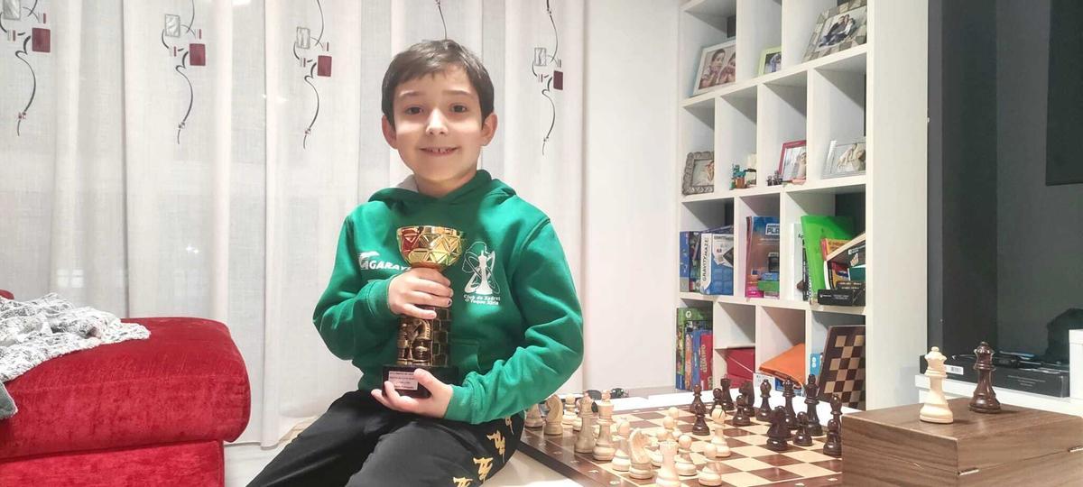 Roi Bello, con uno de sus trofeos y su inseparable tablero de ajedrez