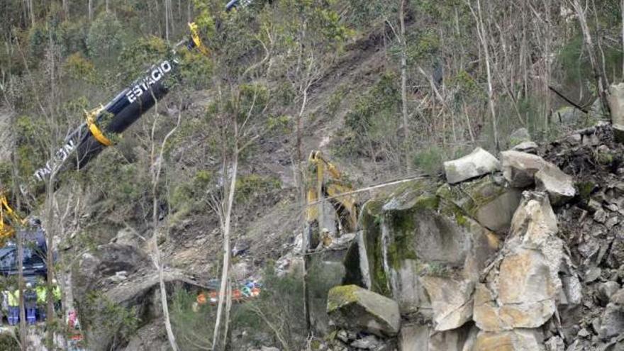 Una grúa trata de levantar la piedra que cayó sobre la excavadora.  // Noé Parga