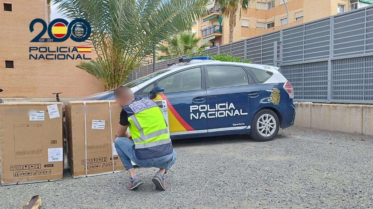 Un policía nacional junto a dos electrodomésticos recuperados en Alicante.