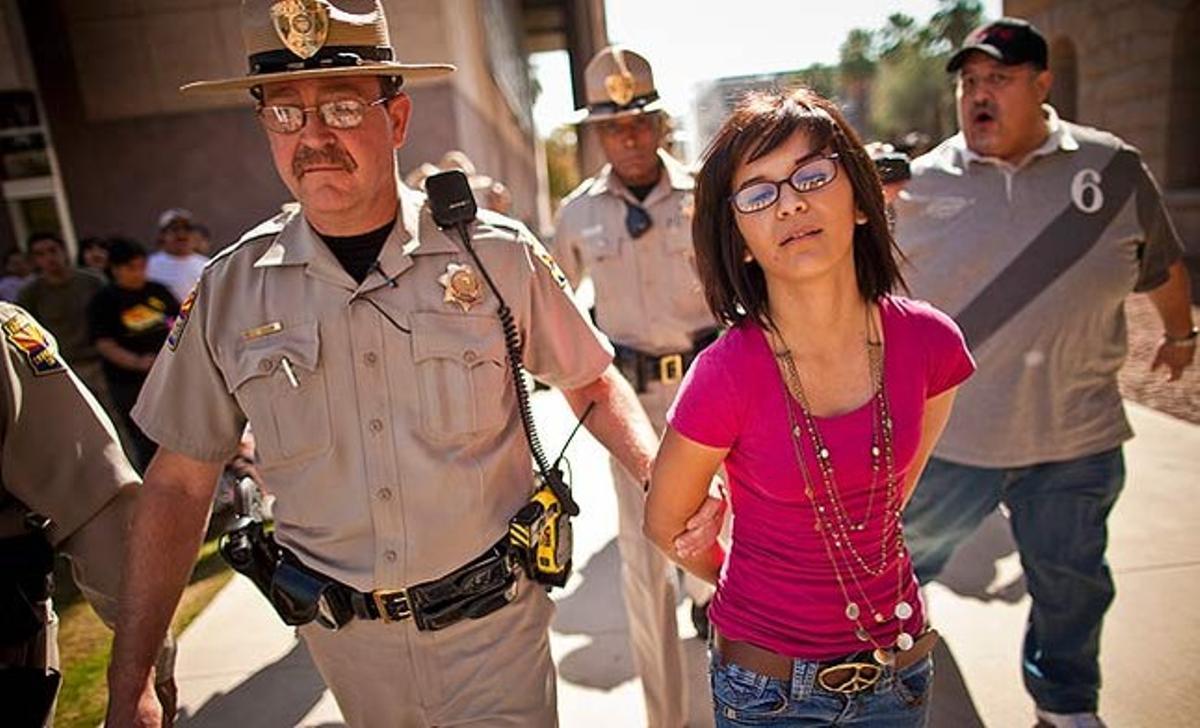 La policia arresta una manifestant al capitoli estatal de Phoenix (EUA) en el transcurs d’una protesta per un projecte de llei que atacaria la immigració il·legal en matèria de vivenda, drets socials i laborals.