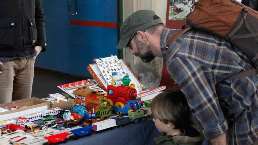 Padre e hijo contemplan una muestra de trenes de juguete.