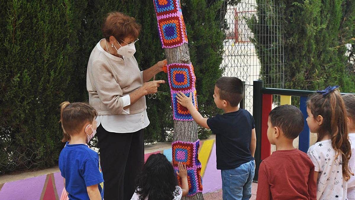 Un grupo de escolares del colegio Hellín Lasheras y una abuela decorando ayer árboles del centro educativo | ISRAEL SÁNCHEZ