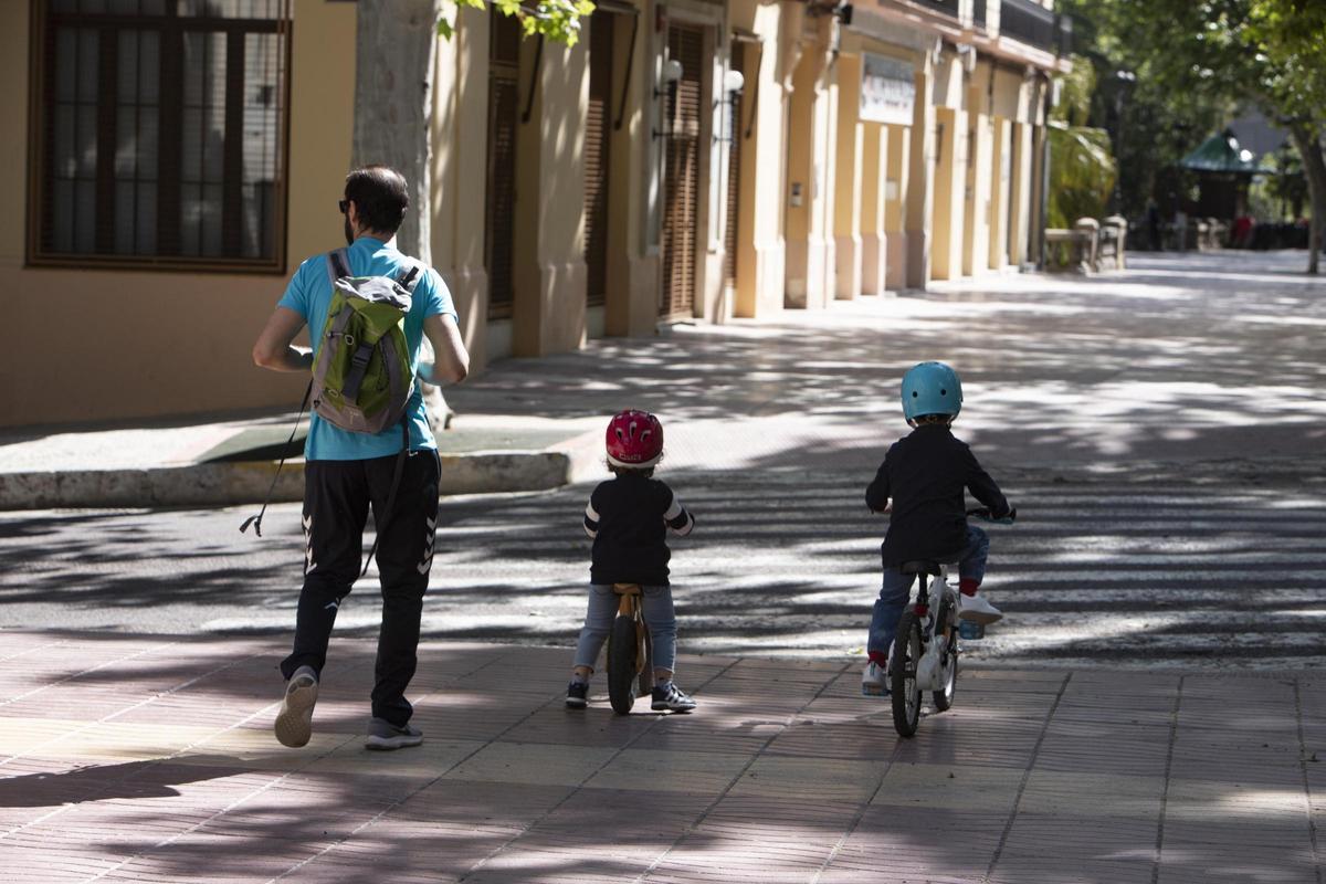 Dos niños en bicicleta, junto a su padre, circulan por la Albereda de Xàtiva, en una imagen de archivo.