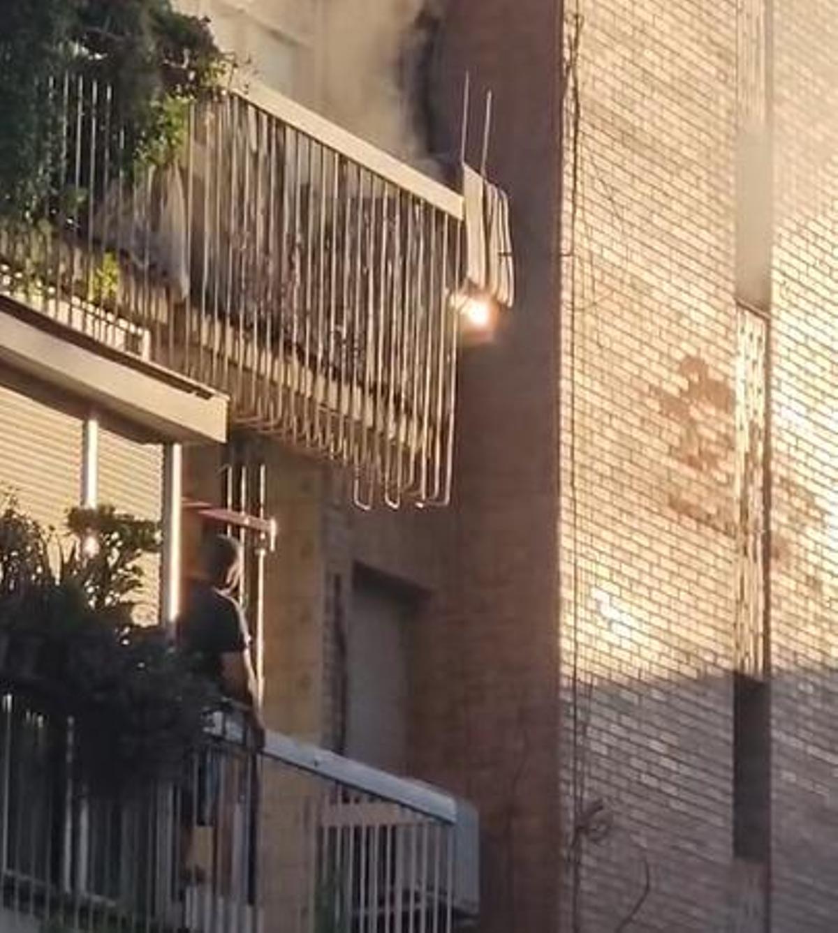 Un vecino observa la columna de humo saliendo del piso superior.