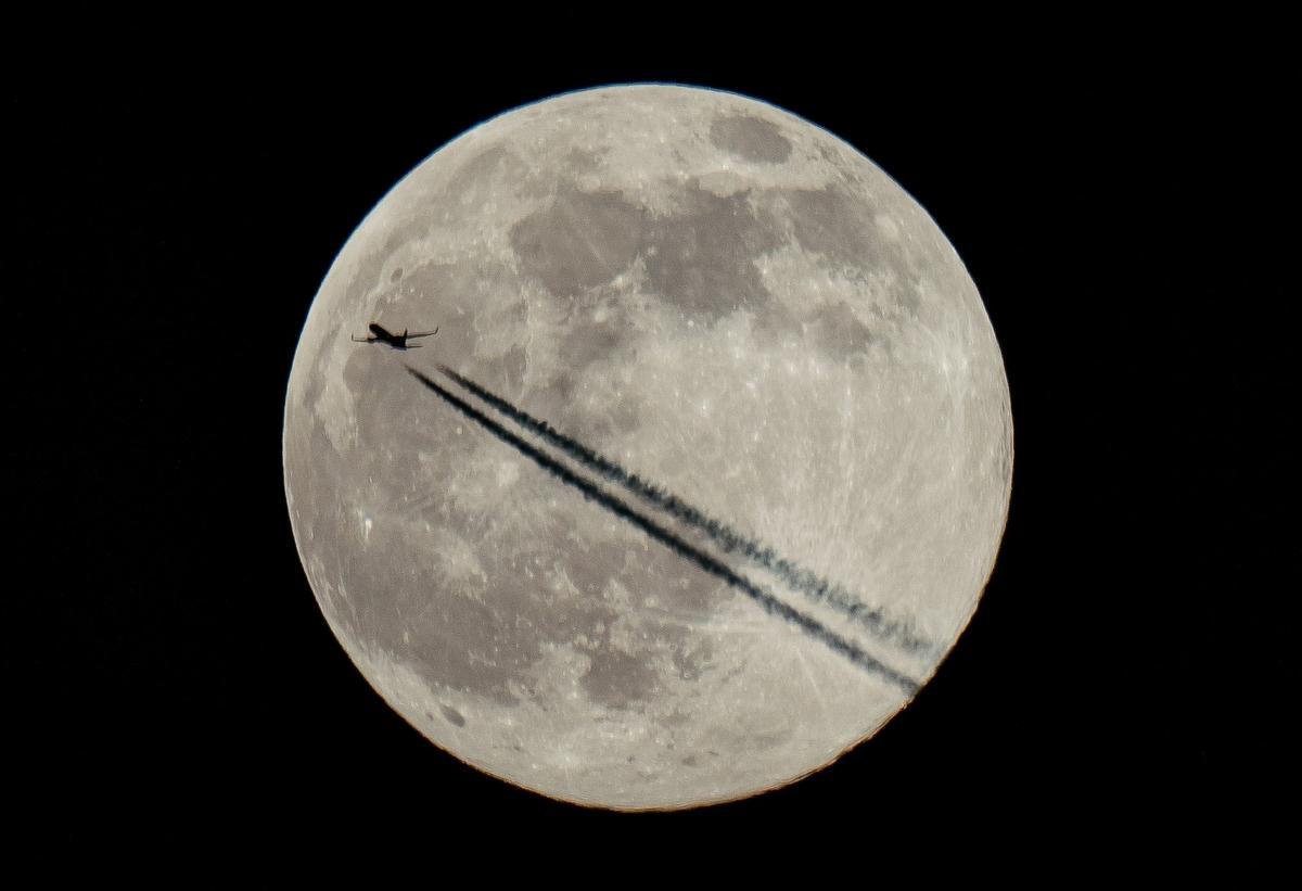 Un avión surca el cielo del Reino Unido en la primera luna llena de 2022. 