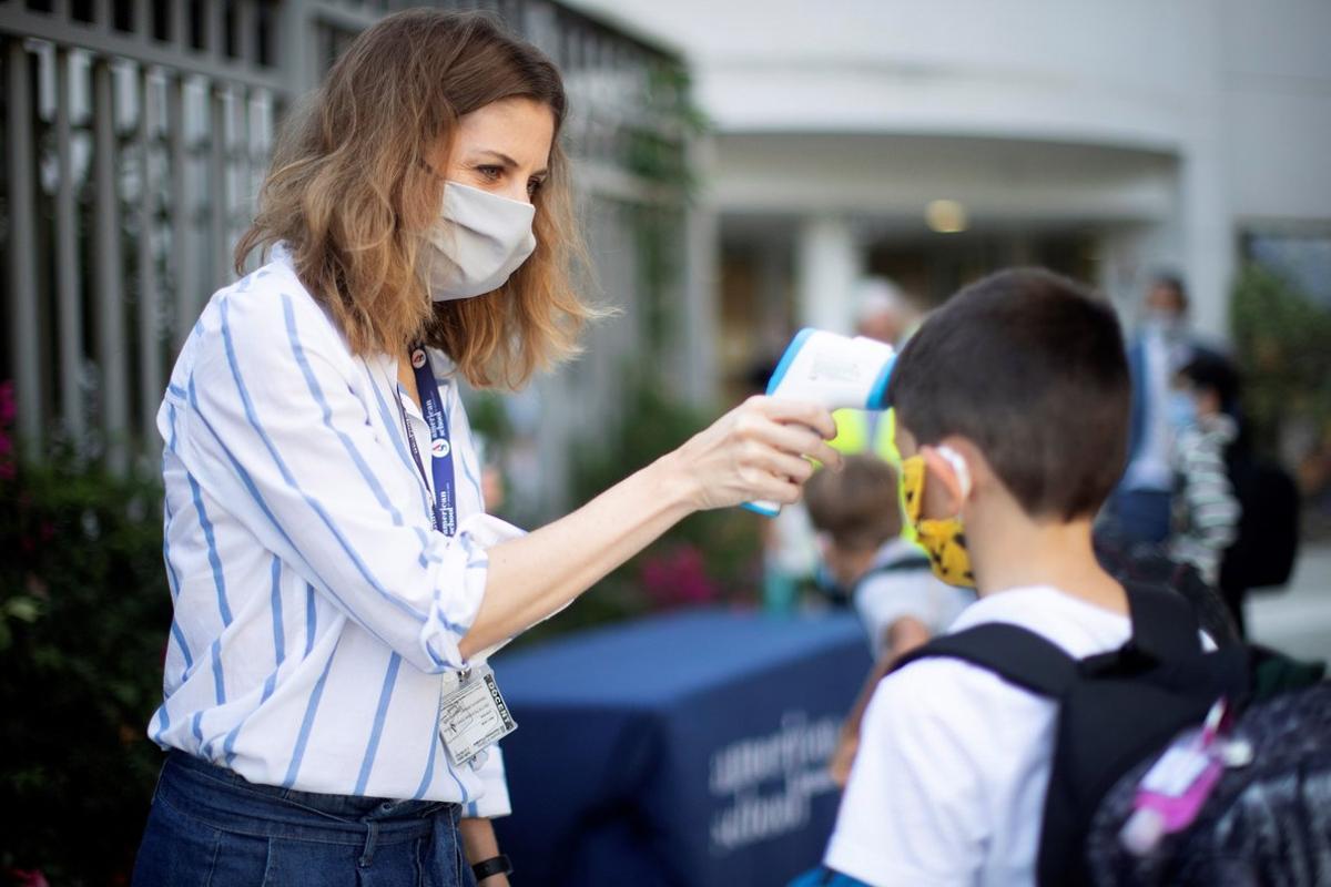 GRAF8035. BARCELONA, 01/09/2020.- Una trabajadora toma la temperatura a un niño a la entrada del colegio privado internacional American School of Barcelona, situado en Esplugues de Llobregat (Barcelona), este lunes. Este colegio, con 890 alumnos, es el primero en España que inicia el curso con medidas anticovid. EFE/ Marta Perez