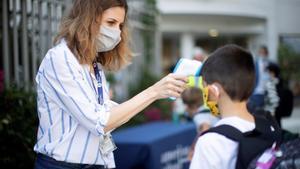 GRAF8035. BARCELONA, 01/09/2020.- Una trabajadora toma la temperatura a un niño a la entrada del colegio privado internacional American School of Barcelona, situado en Esplugues de Llobregat (Barcelona), este lunes. Este colegio, con 890 alumnos, es el primero en España que inicia el curso con medidas anticovid. EFE/ Marta Perez