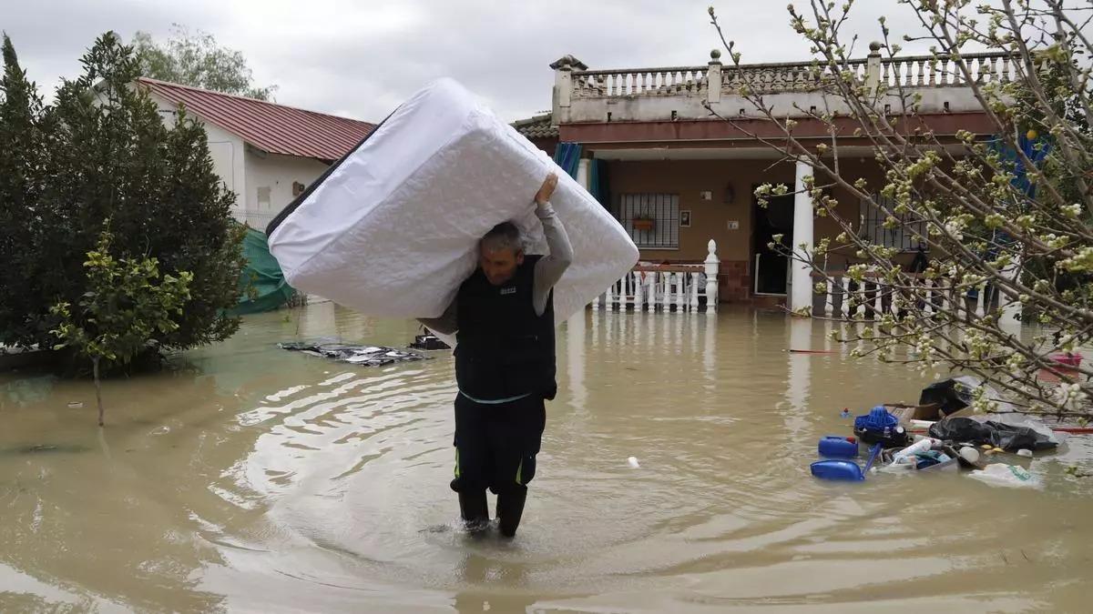 Un vecino de Guadalvalle saca de su vivienda un colchón con el agua a la altura de las rodillas, durante la última crecida del Guadalquivir.