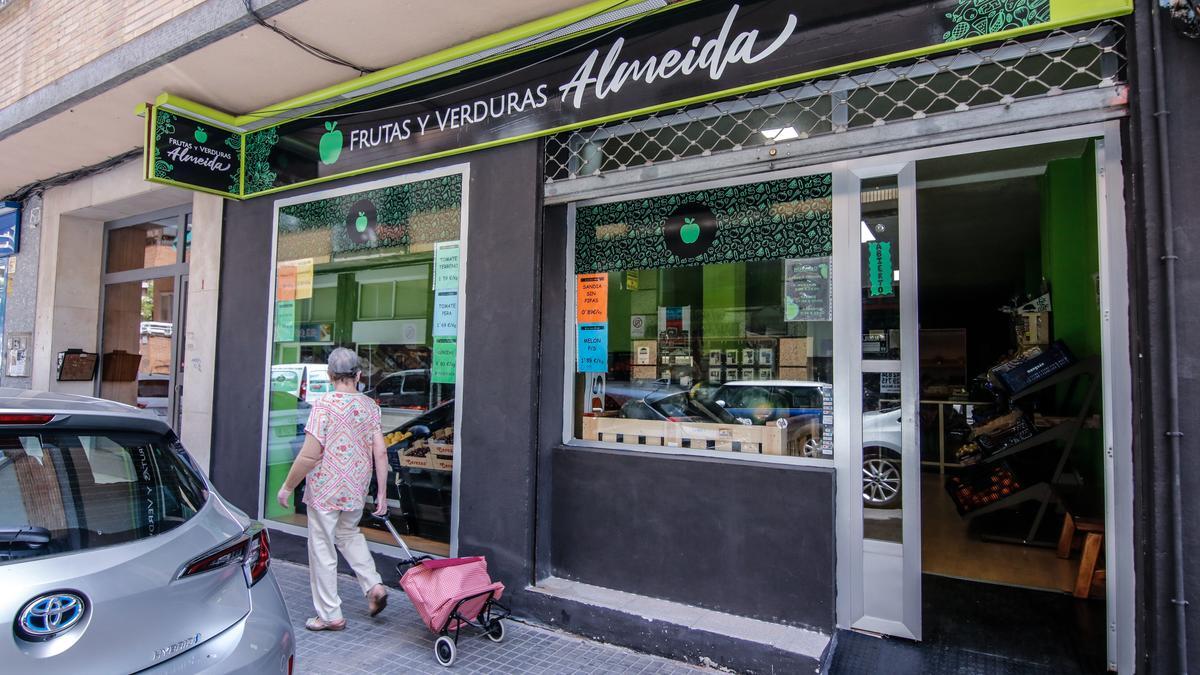 Señora pasando con su carrito de la compra delante de Frutería Almeida, en la calle Arturo Aranguren de Cáceres.