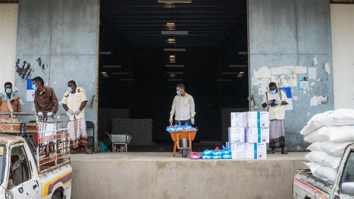 Trabajadores humanitarios llevan bolsas de comida a un camión que las distribuirá, en Abyan (Yemen)