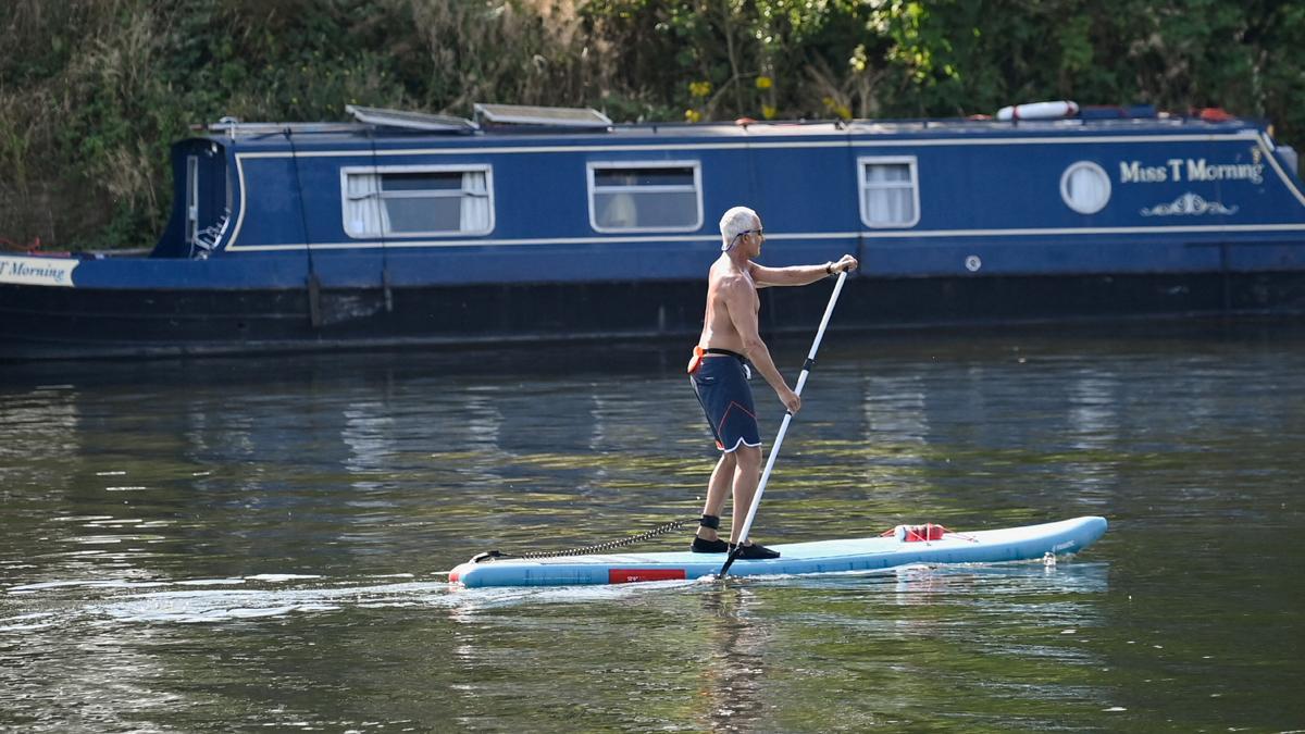 Un hombre se desplaza por el río Támesis con una tabla de paddle surf, a la altura de Shepperton, cerca de Windsor, en Gran Bretaña.