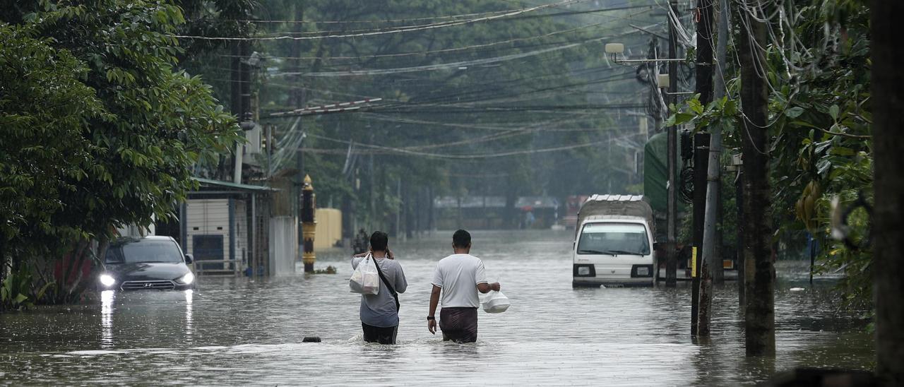 Dos personas caminan en una calle inundada tras una tormenta extrema en Bago, en Myanmar.
