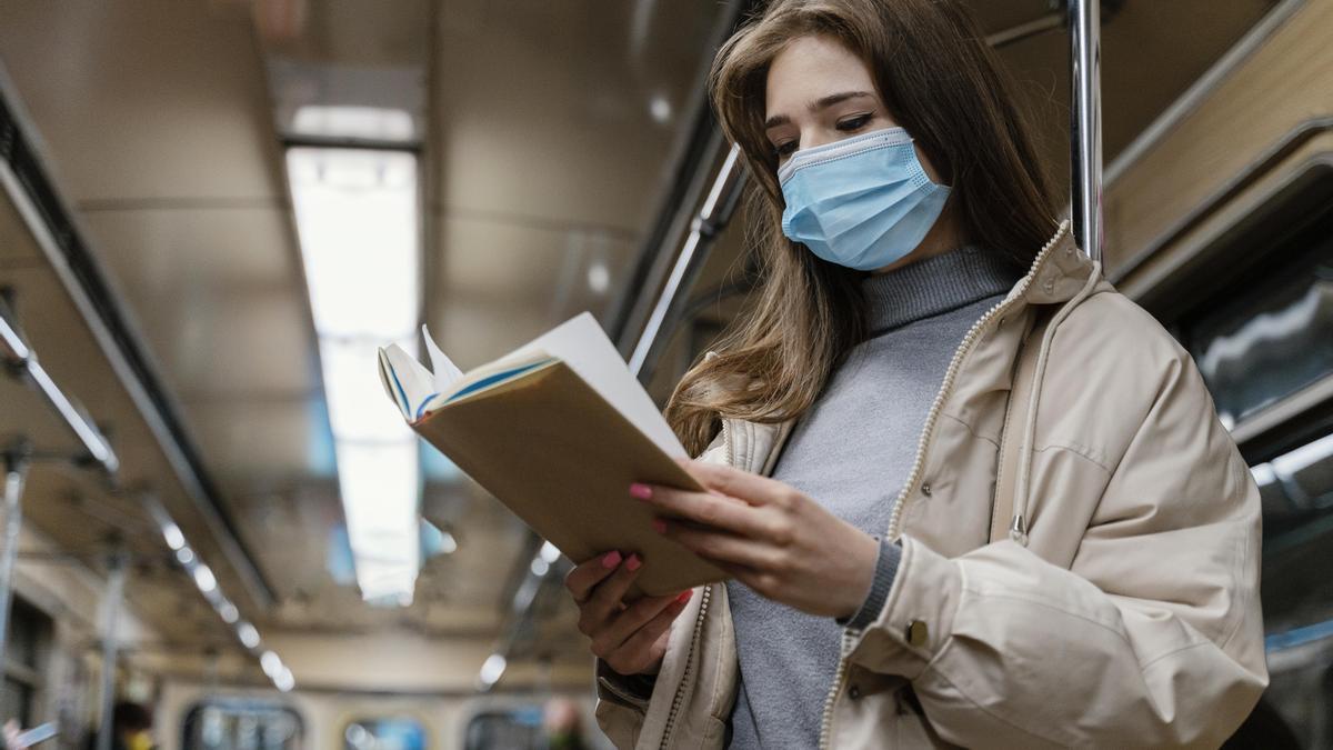 Una joven lee un libro mientras viaja en metro.