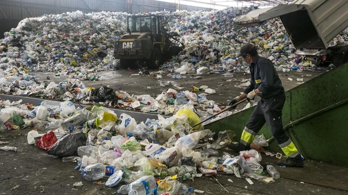 Un operario amontona residuos en la planta de reciclaje de Gavà y Viladecans