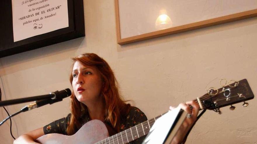 La cantautora interpreta una canción para los asistentes a la presentación, ayer, en Oviedo. En primer término, su poemario.