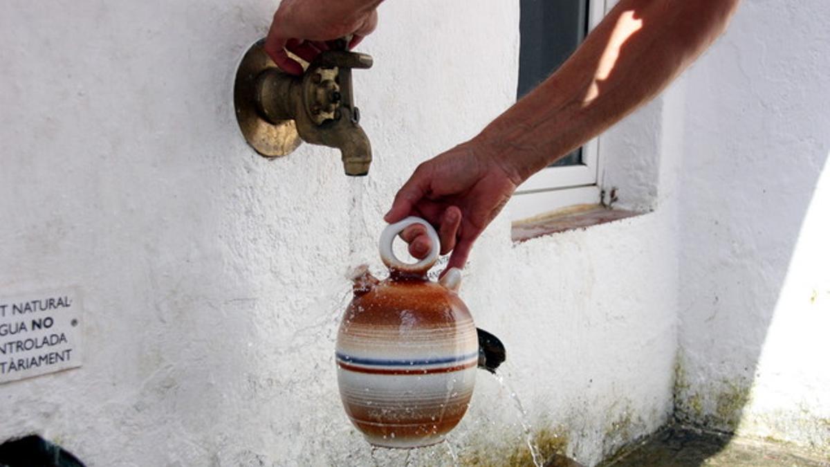 Un hombre llenando el 'càntir de l'any' con agua de la fuente de Sant Domènech en Argentona.