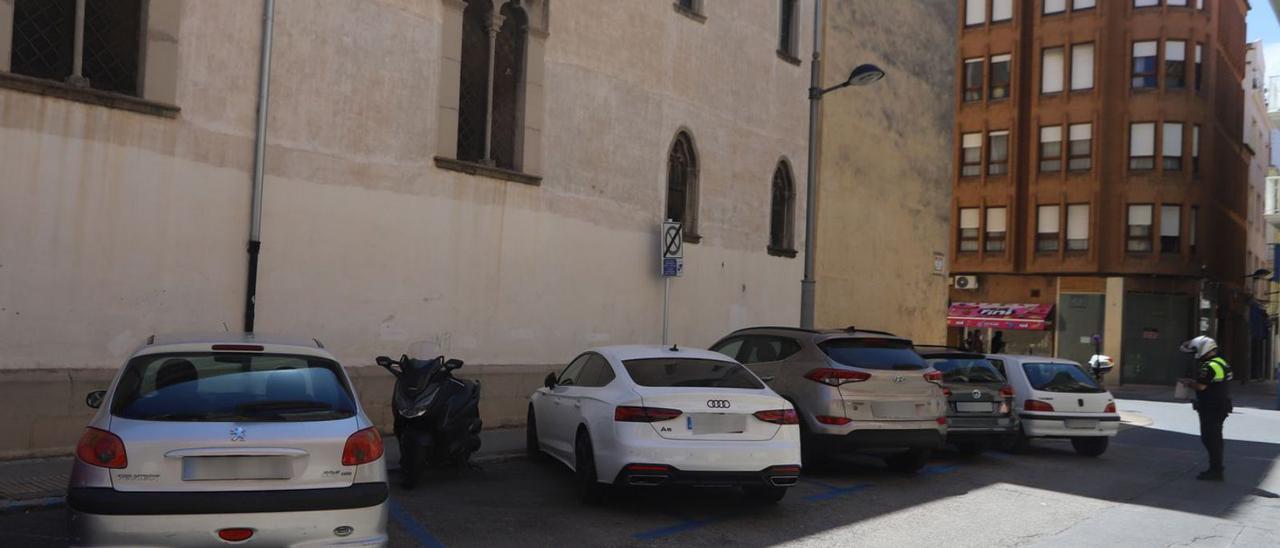 Una moto aparcada ayer en la zona azul de la calle Jesuïtes, entre coches, con un policía cerca.                                 | LEVANTE-EMV