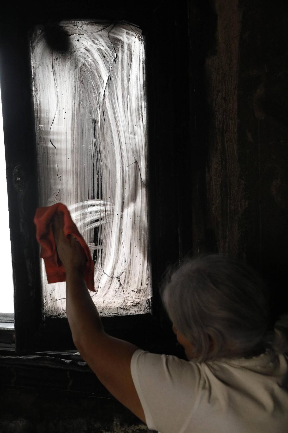 Una mujer limpia la ventana del portal.