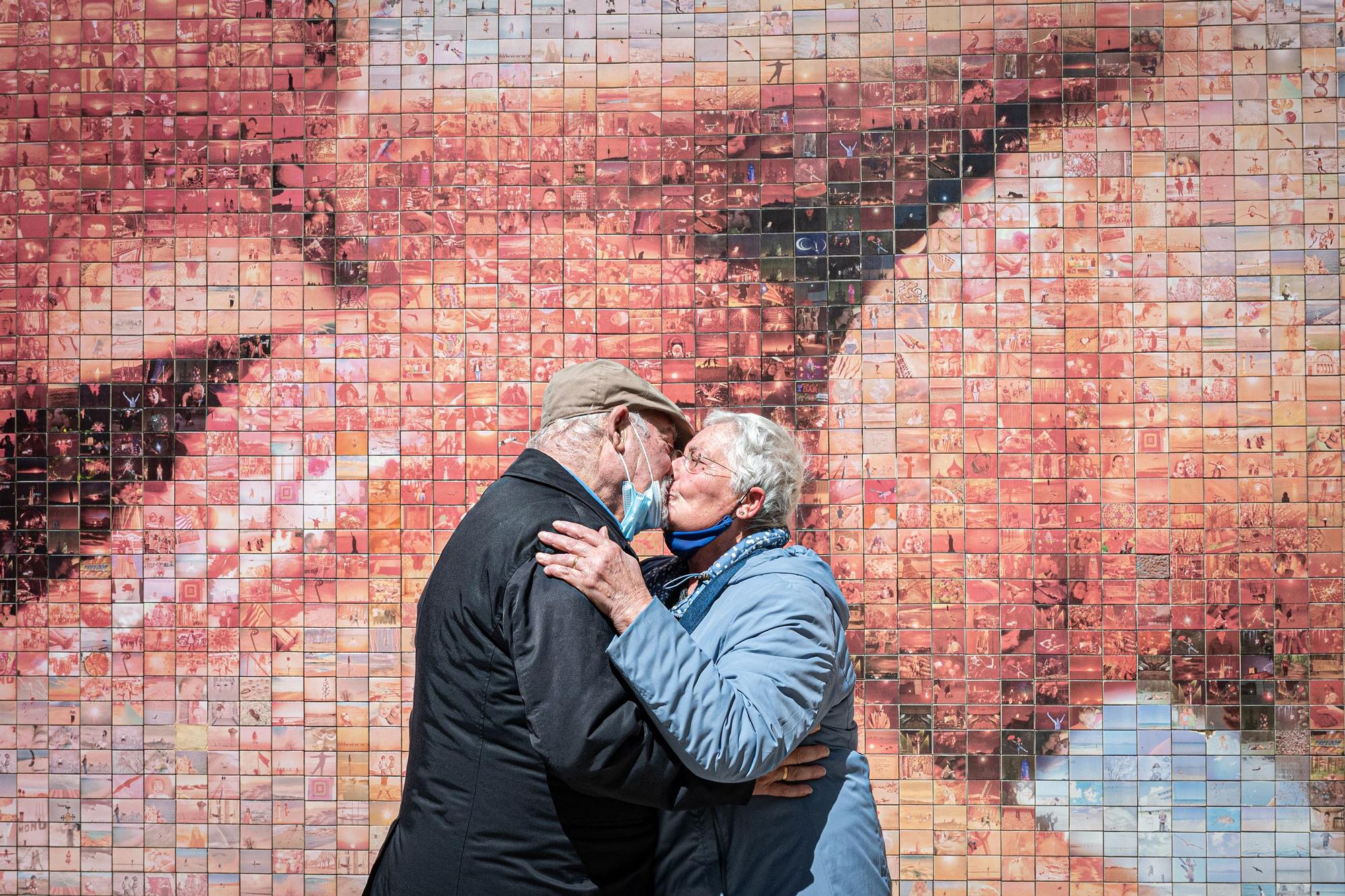 Un matrimonio se besa en Barcelona frente al mural del beso en el Barrio Gótico.
