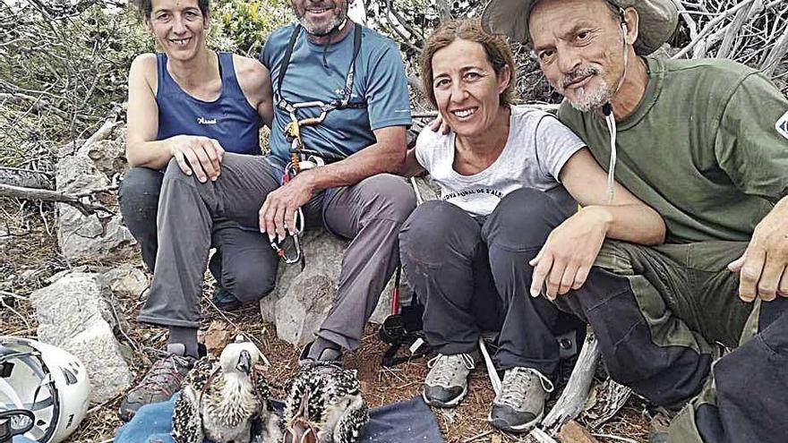 Los expertos posan con las dos crías de águila pescadora.