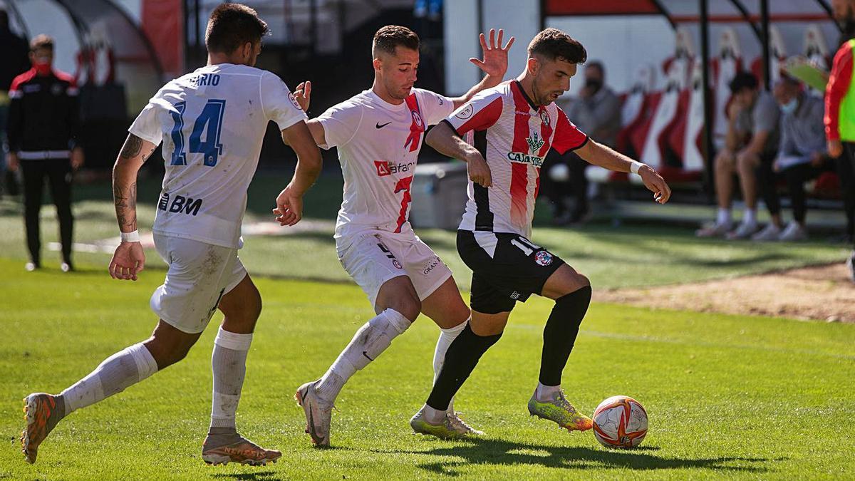 Carlos Ramos trata de avanzar con dos defensores rivales presionándole.