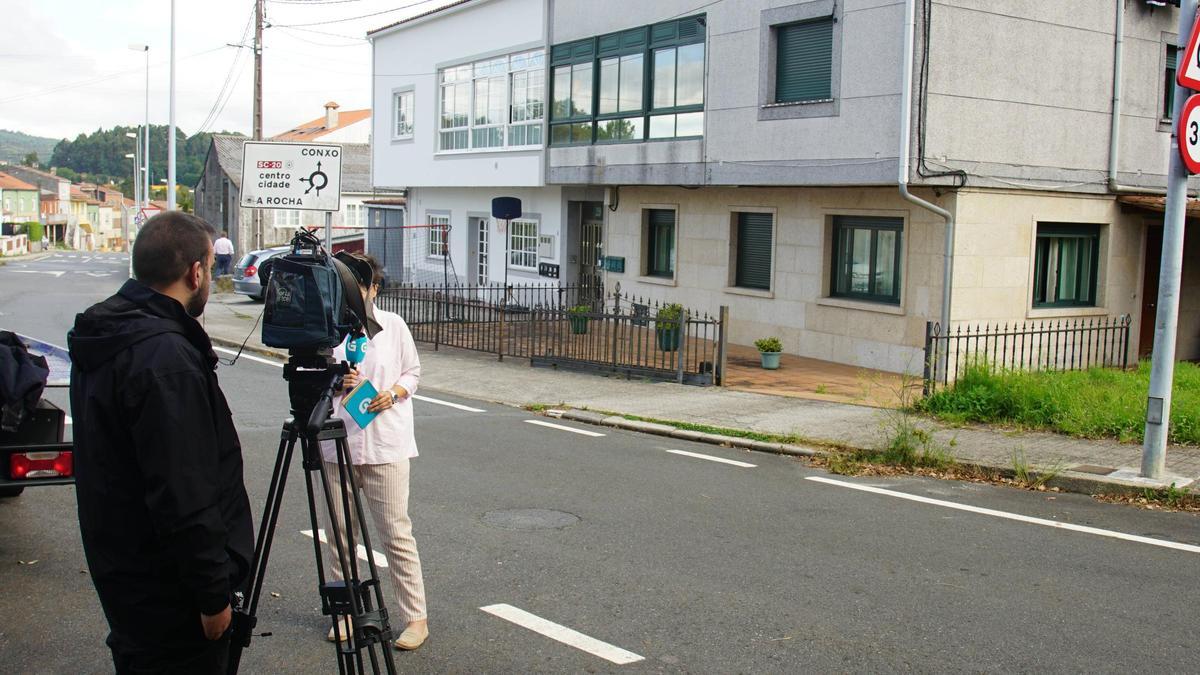 Una reportera informa delante de la casa de la víctima en la calle de Poza Real de Arriba, en Conxo